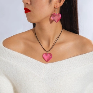 Close-up of pink resin heart pendant necklace and matching earrings on a model