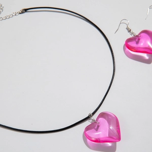 Detail of pink resin heart pendant with black cord necklace and matching earrings