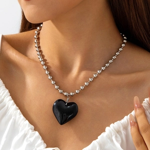 Primer plano de un gran colgante de corazón negro brillante en una cadena de cuentas de plata