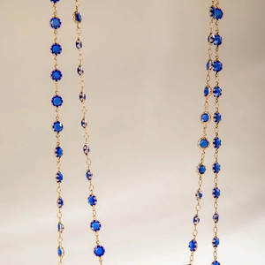 Detalle macro de collares dorados con cristales azul oscuro facetados engastados en garras