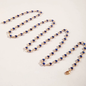 Detalle de collar largo en forma de Y con cuentas azul oscuro y eslabones bañados en oro