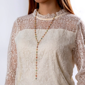 Detalle de un collar en Y con borlas de mariposas de colores en modelo con encaje blanco