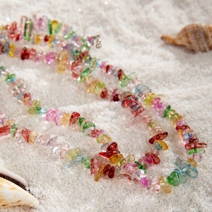 Detalle de cuentas de colores y piedras de cristal en playa con decoro de conchas