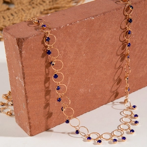 Detalle de collar en Y dorado de varias capas con cuentas de cristal azul oscuro