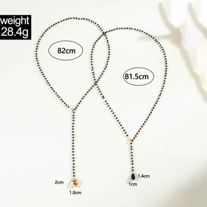 Detailed view of beaded layered necklaces with gold heart and black teardrop pendants