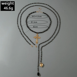 Detailed view of layered beaded necklace with gold cross, heart, and water drop pendants