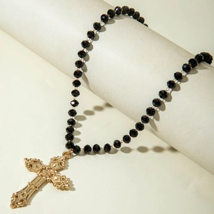 Detail of vintage layered Y-necklace with black faceted beads and embossed gold cross