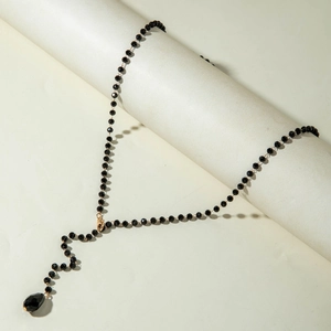 Detail of beaded Y-shaped long necklace with faceted black beads and teardrop pendant