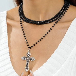 Detailed view of layered beaded necklace with an ornate silver gothic cross pendant