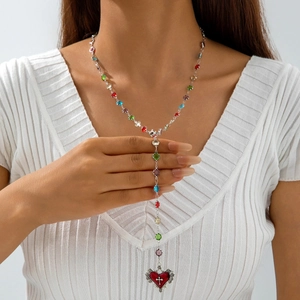 Detail of bohemian Y-shaped beaded necklace with red heart pendant and cross motif