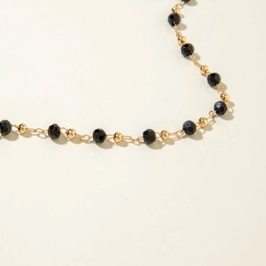 Macro detail of multi-layered beaded necklace with black faceted and gold round beads