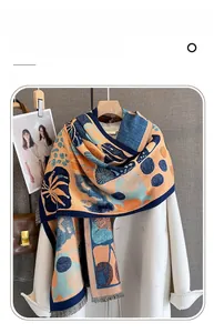 Dettaglio di sciarpa in finto cashmere con motivi floreali arancioni e blu e frange