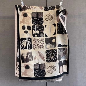 Dettaglio di sciarpa jacquard con motivi a foglie astratte e bordi a frange