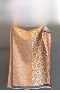 Vue détaillée des motifs Paisley sur une écharpe bicolore orange et beige doux