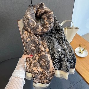 Detail of vintage paisley pattern on thick beige and black cashmere-like scarf with tassels