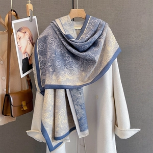 Detail of blue-grey bohemian shawl with vintage floral patterns on a white coat