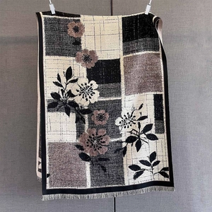 Detail of floral and geometric plaid patterns on a cashmere-feel shawl with tassel fringe