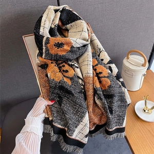 Detail of autumn cashmere-feel shawl featuring orange floral prints and black tassels