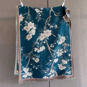 Close-up of woven cashmere-feel scarf with magnolia flower print and tassel edges