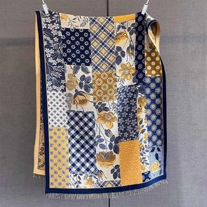 Detail of floral and plaid patchwork shawl showing frayed fringe and rich patterns