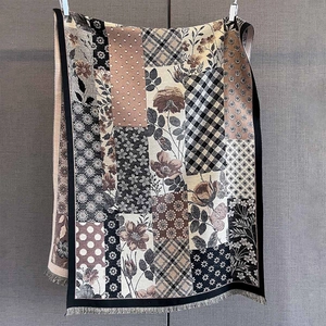 Close-up of vintage floral patchwork knit scarf featuring elegant fringe and tassel details