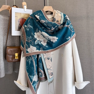 Thick cashmere-like floral scarf with tassels draped over a coat for autumn warmth