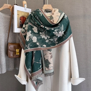 Detail of floral cashmere-feel scarf with fringe edges over a beige coat