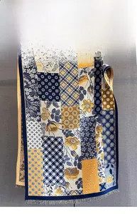 Detail of plaid and floral print scarf with navy blue piping and decorative tassels