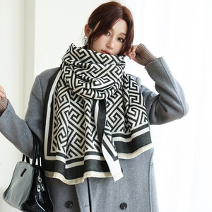 Détail d'une écharpe d'hiver douce avec motifs à grecques noir et blanc et franges