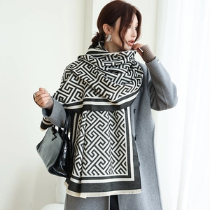 Femme élégante portant une écharpe géométrique noire et blanche à franges sur un manteau gris