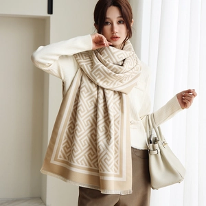 Détail d'une écharpe en maille beige avec motif géométrique et bords à franges délicats