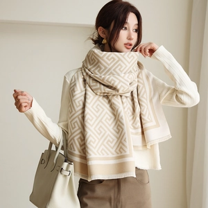 Détail d'une écharpe d'hiver montrant un motif grec beige et une texture en maille douce
