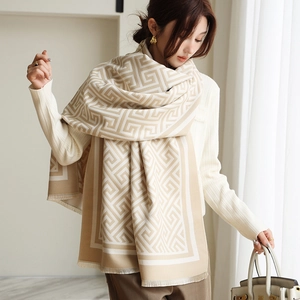 Détail d'un châle pashmina beige avec motifs géométriques et bords à franges délicates