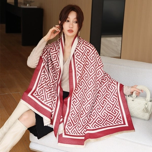 Gros plan sur un châle en cachemire rouge et beige avec motifs grecs et franges
