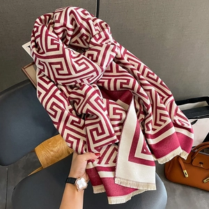 Détail d'une écharpe à motif grec rouge et beige avec franges et texture douce