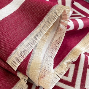 Vue détaillée de la texture de l'écharpe tissée rouge et beige avec des franges douces
