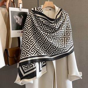 Détail de l'écharpe à motifs géométriques noir et blanc avec franges sur manteau