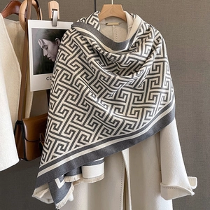 Détail d'une écharpe à motif géométrique crème et gris avec des finitions à franges