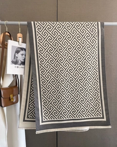 Détail d'une écharpe à motif géométrique gris et beige avec franges et texture douce