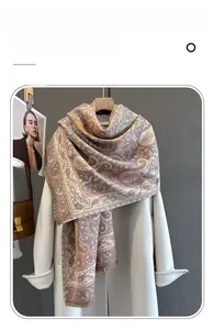 Dettaglio di una sciarpa morbida con stampa paisley e frange su un cappotto bianco