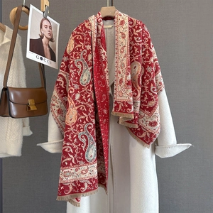 Elegante sciarpa con motivo paisley rosso e nappe color beige su un cappotto bianco