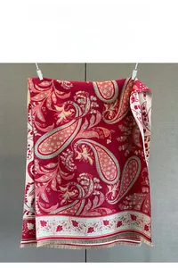 Detail shot of the paisley pattern and fringe edge on a deep red cashmere-style shawl