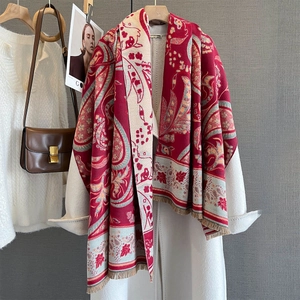 Elegant red and white paisley cashmere scarf with fringe, draped on a white jacket