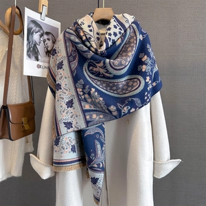 Detail of navy blue paisley jacquard pattern with fringe on soft cashmere-like scarf