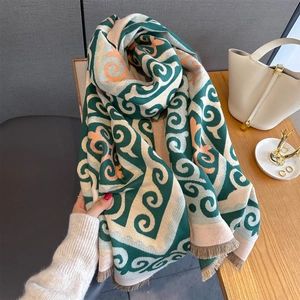 Detail of soft knit shawl scarf with green geometric patterns and delicate fringe trim