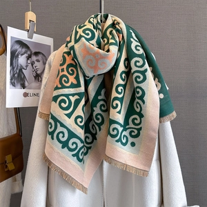 Close-up of winter scarf with geometric pattern and tassels draped on white coat