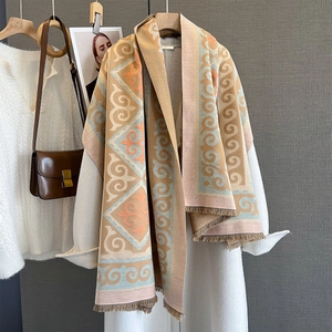 Geometric pattern scarf with fringe styled on white coat over neutral background
