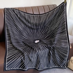 Detail of a black twill silk scarf with white radial lines on a leather sofa