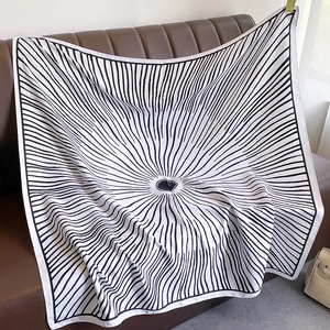Detail of a black and white silk scarf with radial pattern draped on a leather sofa