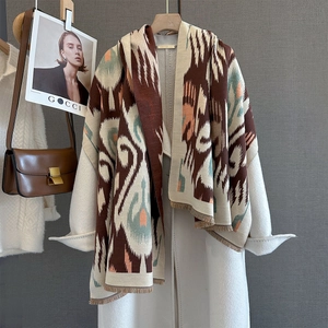 Detailed view of bohemian geometric pattern scarf with fringe on white coat